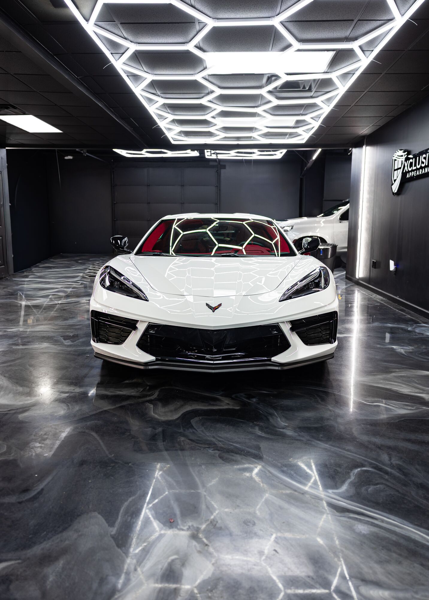 White C8 Corvette in the hex-lit bay