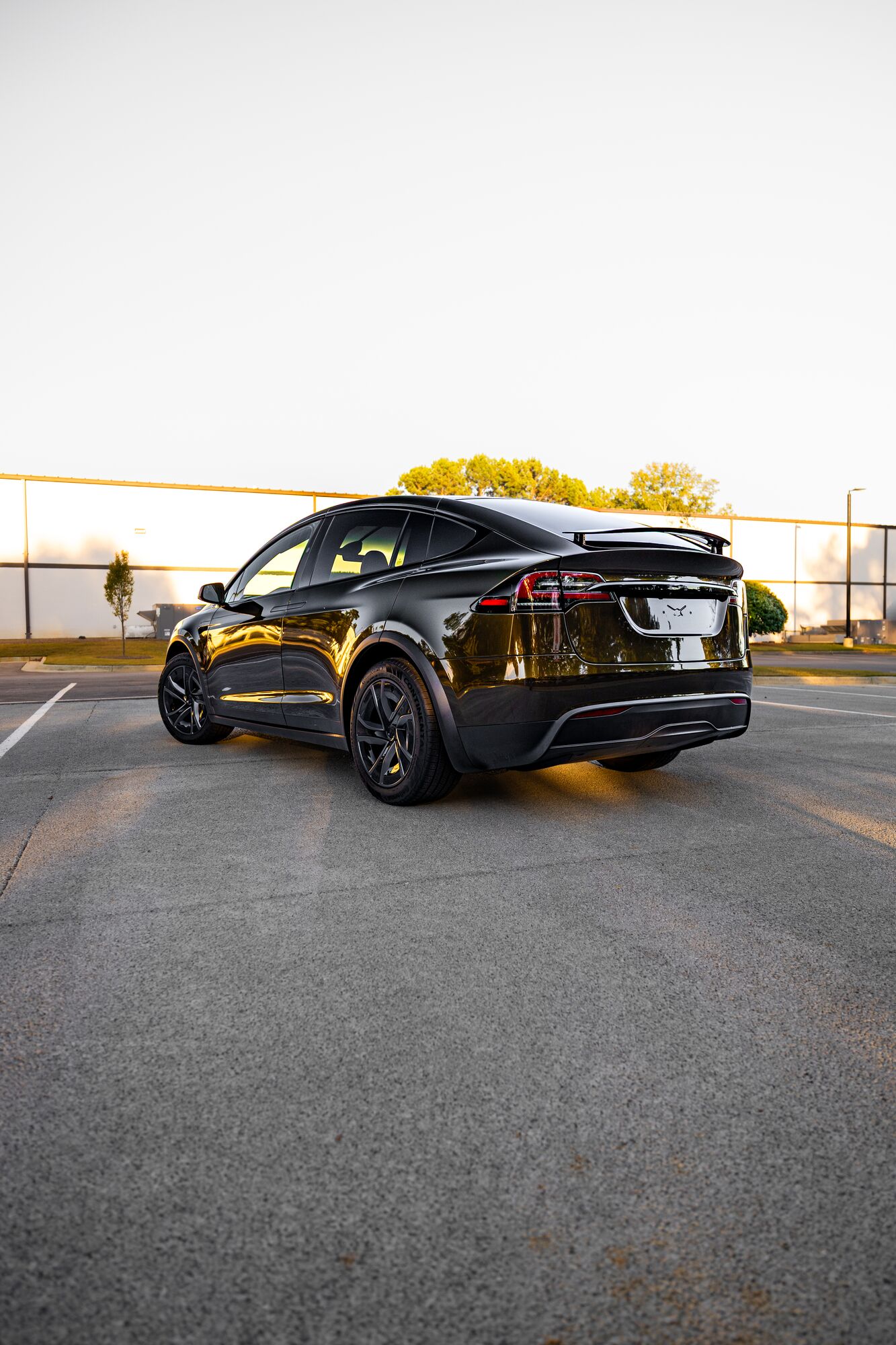 Rear three-quarter view of a Tesla Model X at golden hour